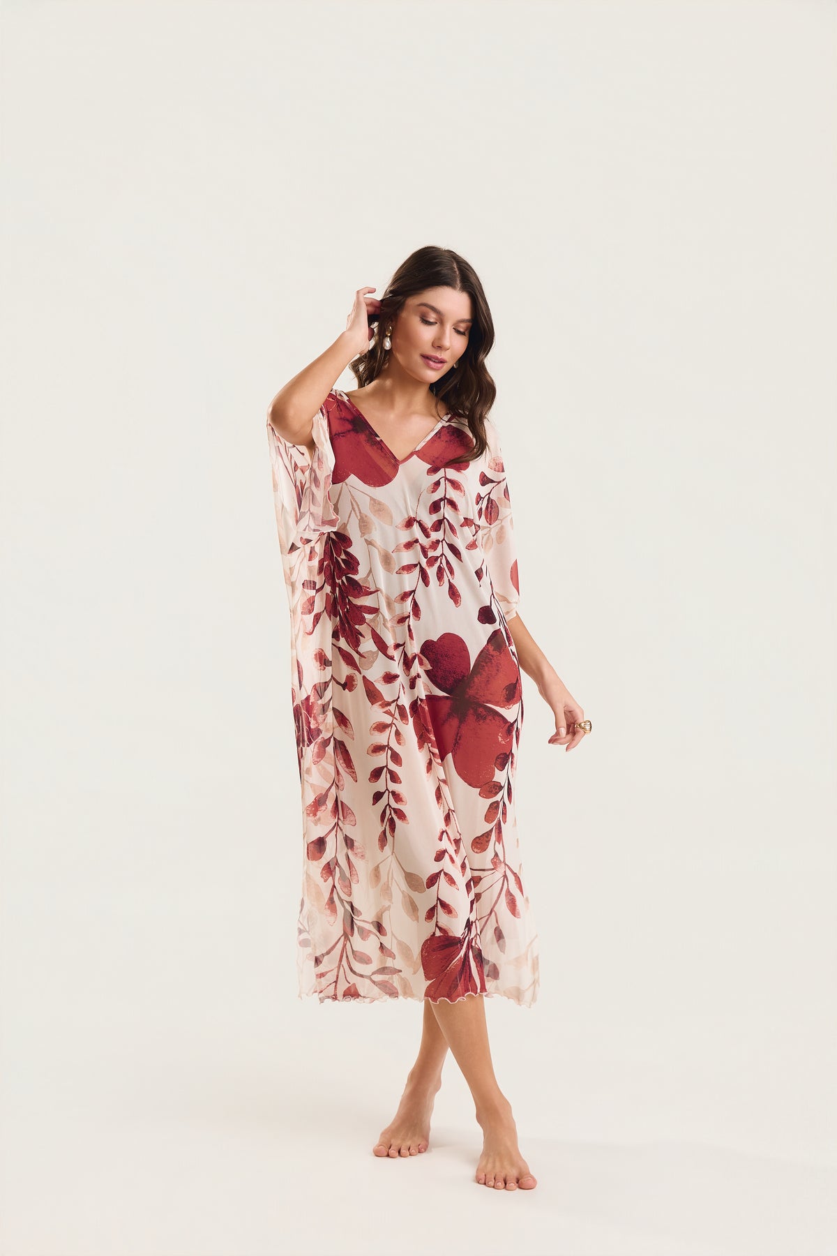 Kaftan Tule Mareblu em tule floral com estampa de flores e folhagens  — modelo de frente com uma mão nos cabelos, postura elegante e relaxada