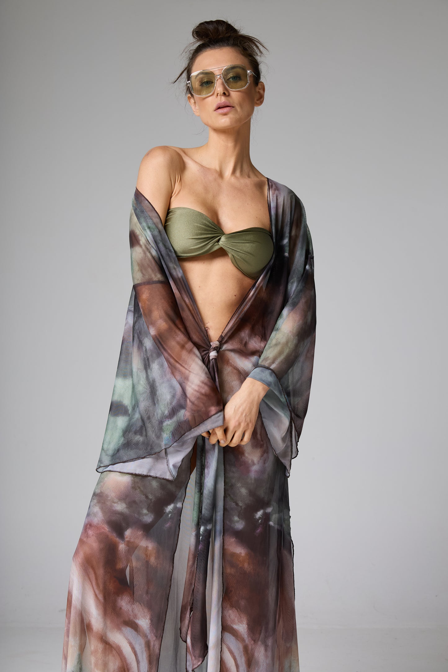 Saída de praia quimono estampado tie-dye com biquíni tomara que caia verde-oliva. A modelo veste a peça aberta amarrada na cintura,