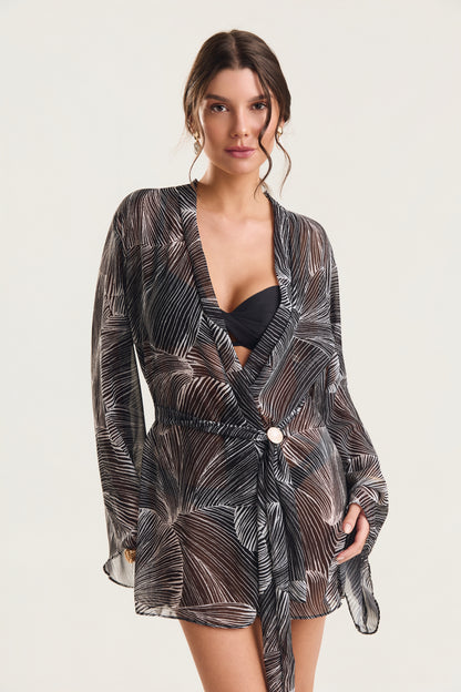 Close no busto do kimono de manga longa com estampa de conchas pretas, modelo em posição frontal levemente inclinada
