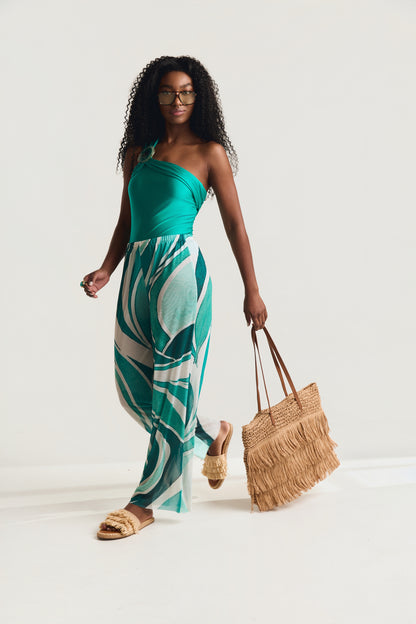 Maiô Um Ombro Pedra Detalhe Franzido Mareblu na cor jade, modelo caminhando de frente usando pantalona geo verde e segurando bolsa de palha com franjas