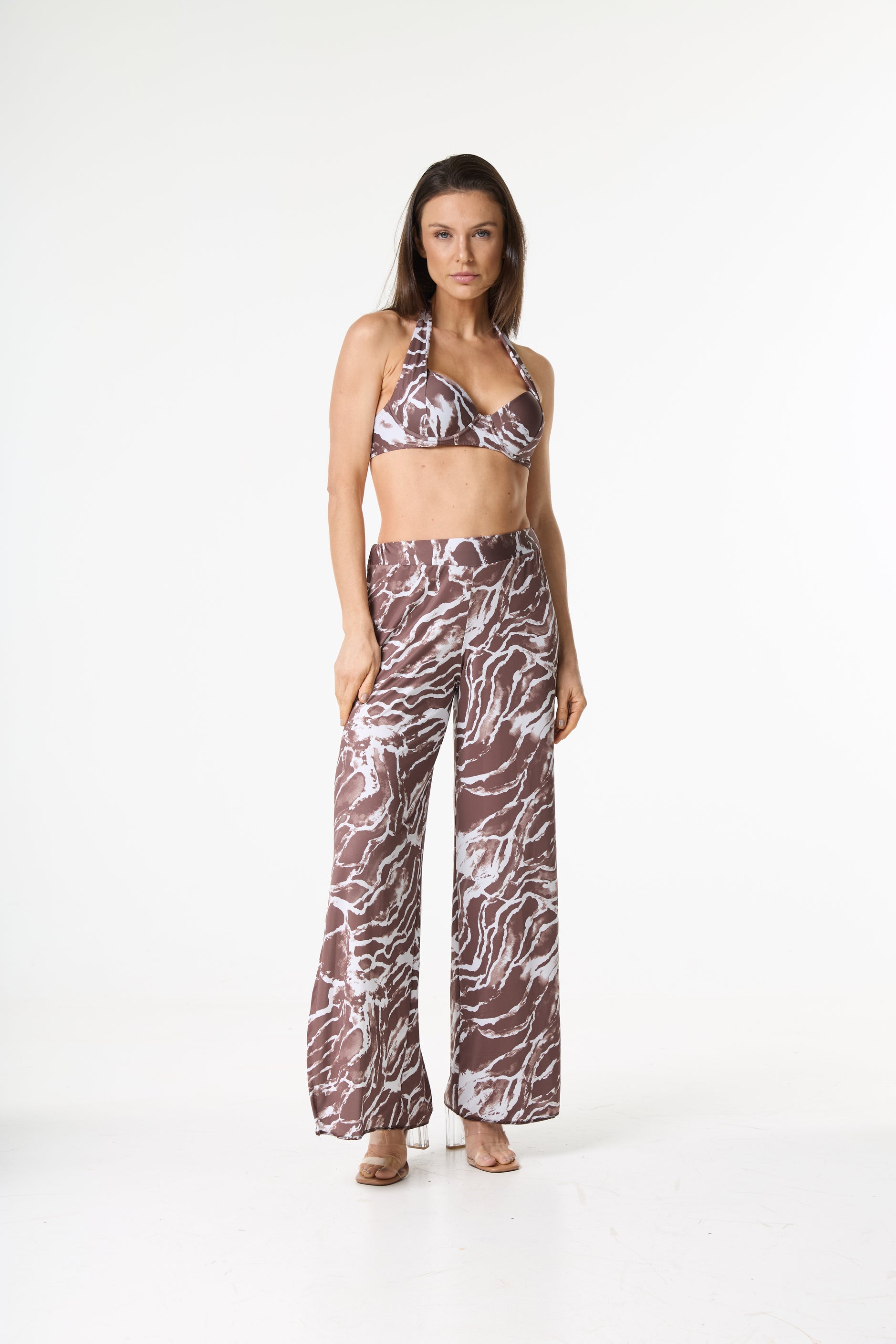 Conjunto halter pants estampa marrom. Modelo em pé de frente, vestindo top halter e calça pantalona fluida com estampa abstrata marrom e branca em fundo branco.