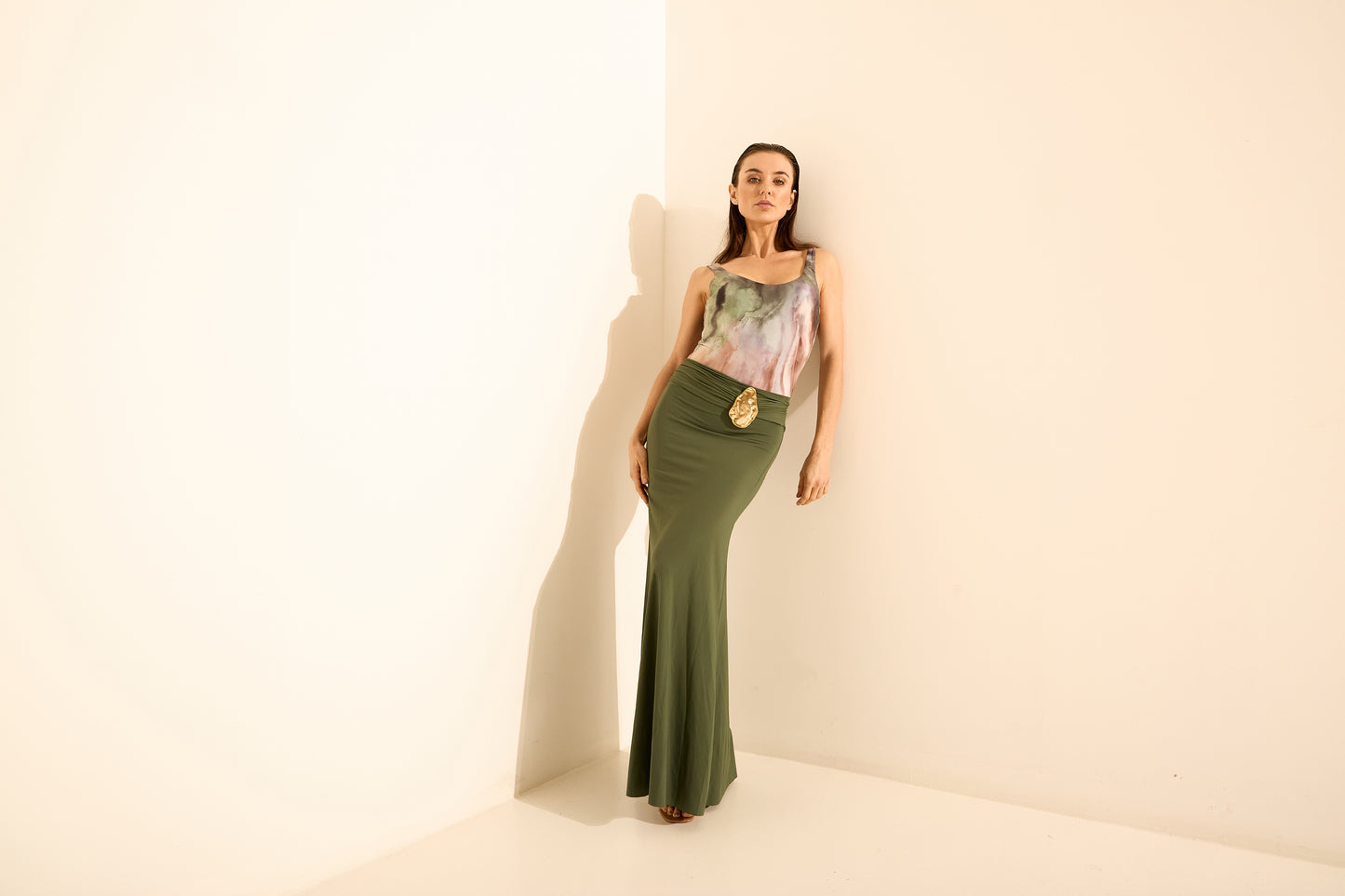 Conjunto top estampado e saia longa verde oliva. O top de alça fina tem estampa abstrata em tons de verde, roxo e rosa, combinado com saia longa verde