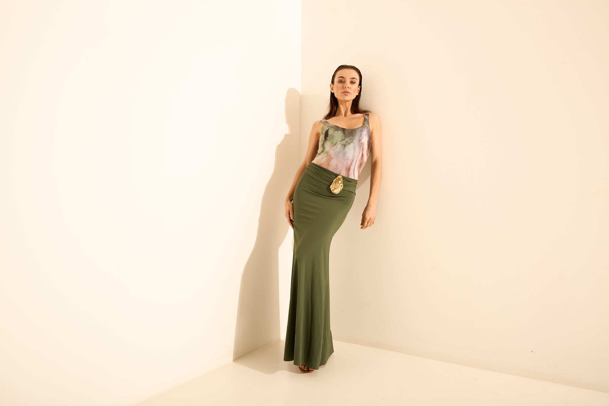 Conjunto top estampado e saia longa verde oliva. O top de alça fina tem estampa abstrata em tons de verde, roxo e rosa, combinado com saia longa verde