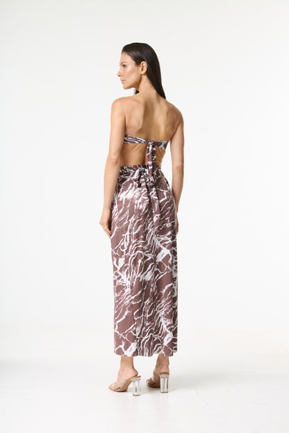 Conjunto de saída de praia com estampa marmorizada marrom e branca. A modelo é vista de costas, com a cabeça virada para o lado, mostrando o top tomara