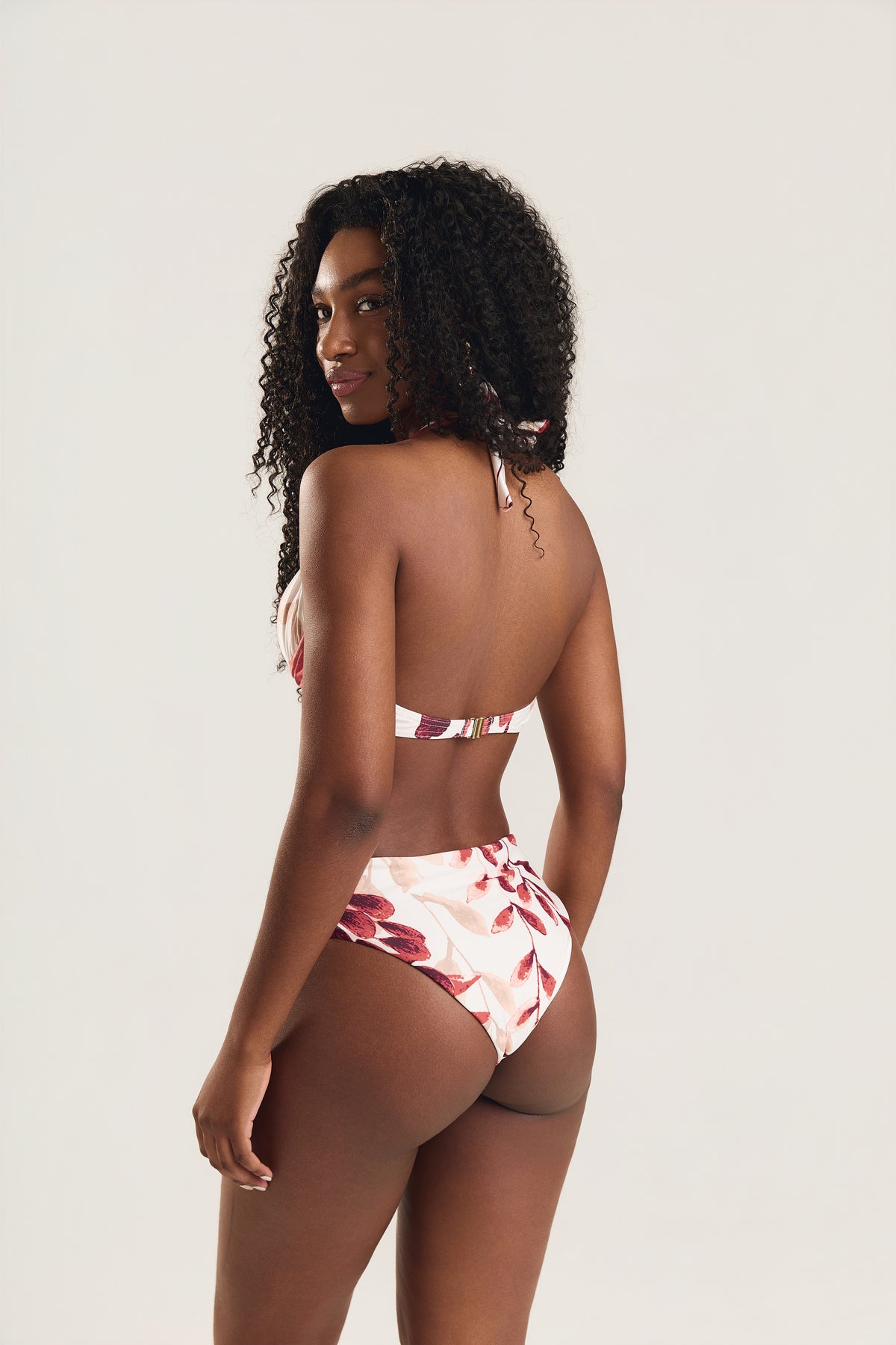 Modelo de costas exibindo o fechamento halter do top e o corte da calcinha franzida alta Mareblu
