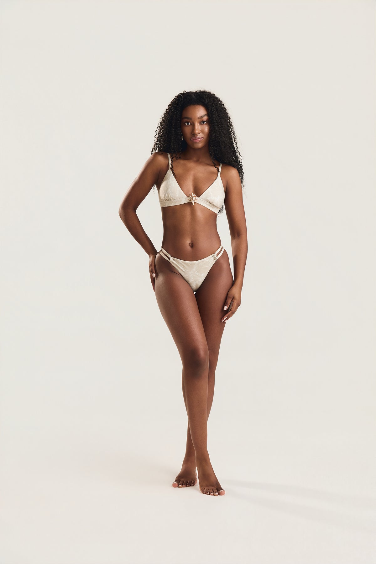Top metal coral e calcinha roletê duplo conchas off white, modelo em posição frontal com corpo inteiro visível e mão na cintura
