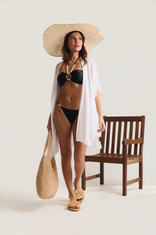Top pérolas e calcinha pérolas preto Mareblu — modelo em posição frontal ereta com chapéu de palha, saída de praia branca aberta, bolsa de palha e sandália de franja, exibindo ambos em look de praia
