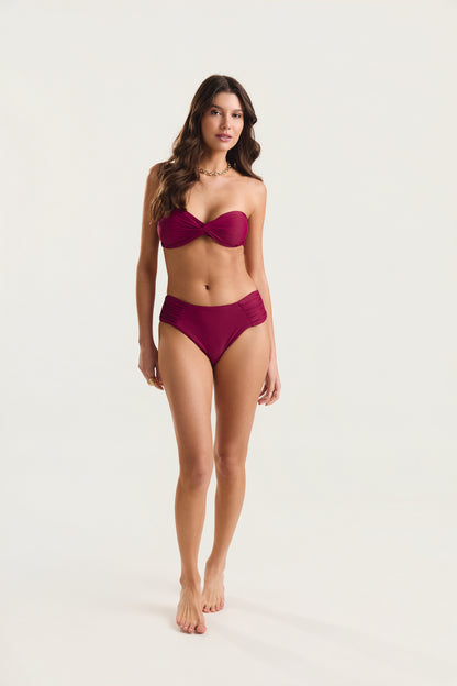 Top tomara que caia franzido e calcinha franzida alta na cor carmim, modelo de frente em posição de passarela, fundo branco
