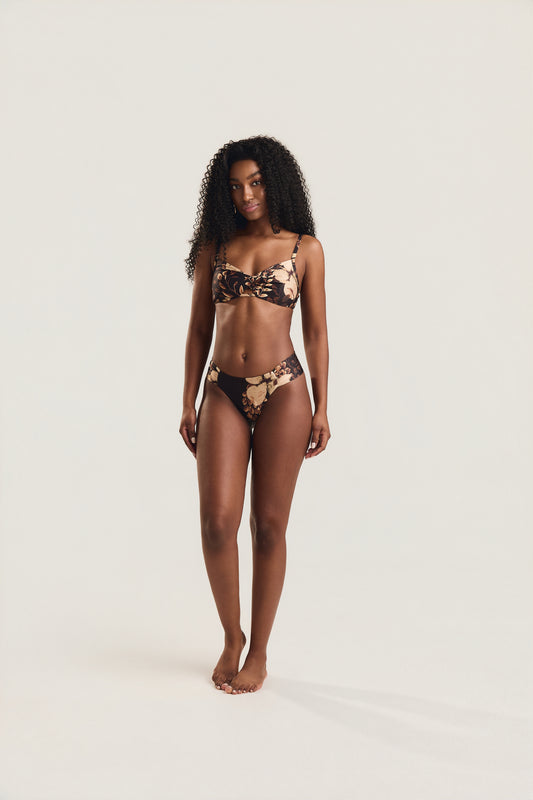 Top torcido e calcinha franzida floral preto, modelo em posição frontal com braços ao longo do corpo
