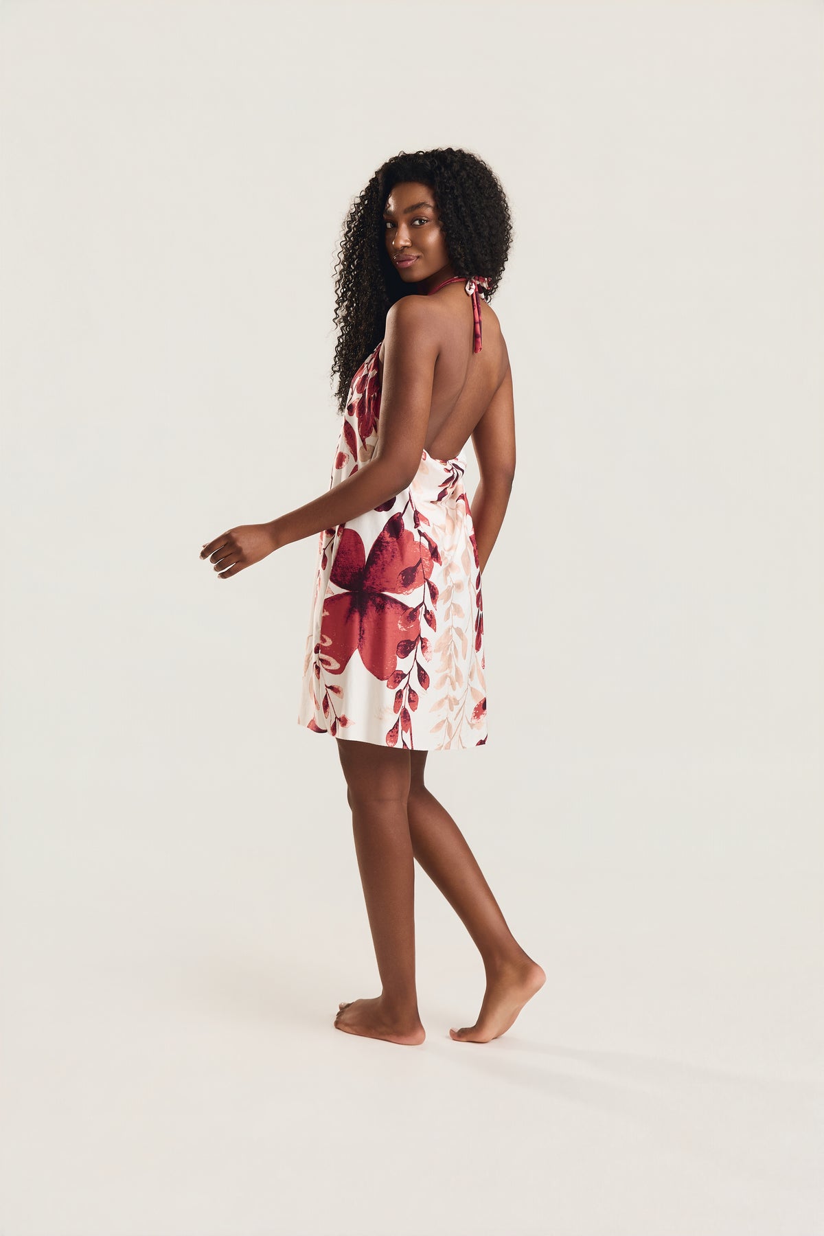 Vestido frente única com estampa foral vermelho e decote nas costas, modelo de lado mostrando decote nas costas 