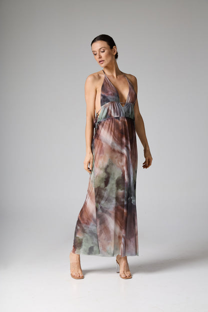 Vestido longo com decote halterneck e estampa abstrata estilo aquarela em tons de marrom, verde e cinza. A modelo está de pé, olhando para baixo.